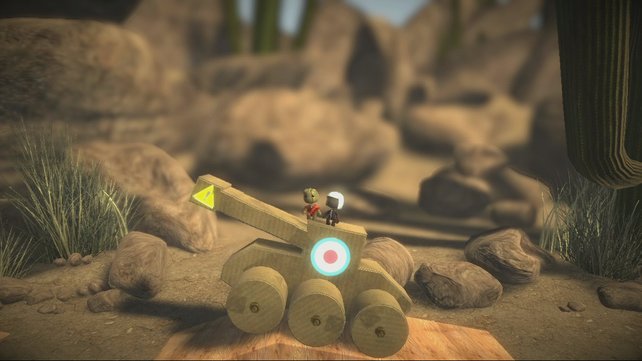Zwei Sackpuppen fahren mit einem Holzpanzer durch das Level.